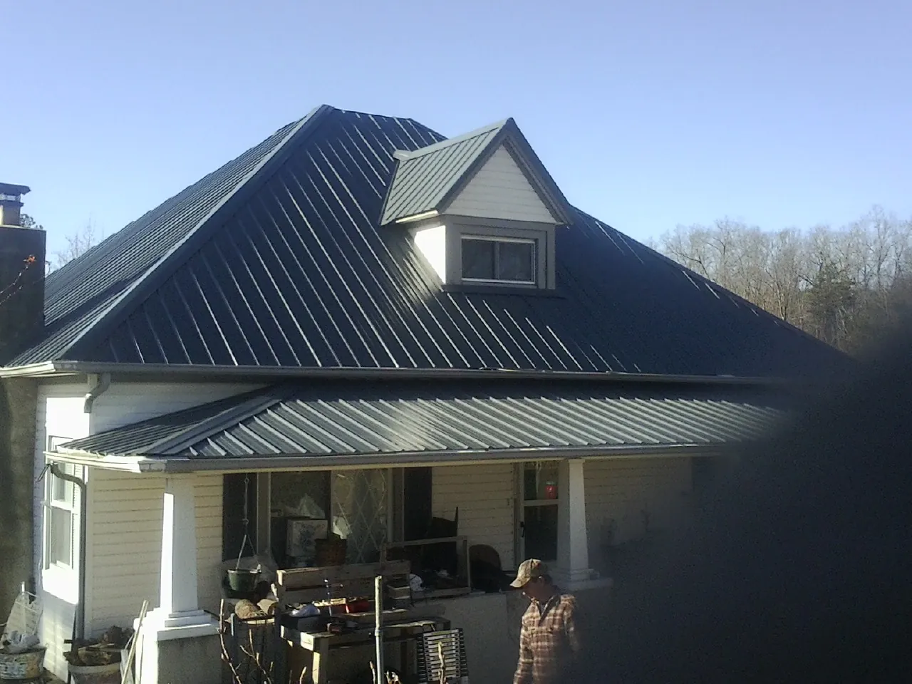 Dark blue standing seam metal roof with a dormer above a front porch in Leeds